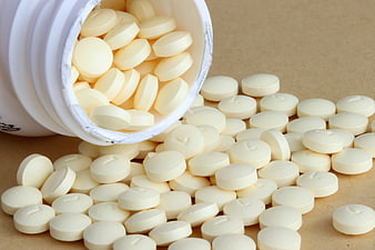 White Pharmaceutical Tablets Spilling From Plastic Bottle On Brown Surface
