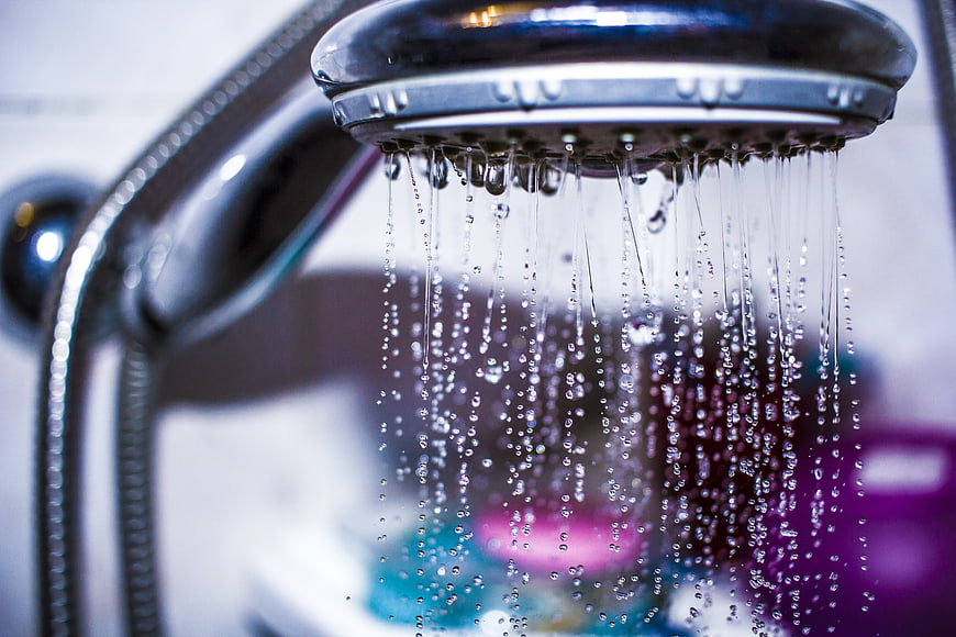 Close-up of a chrome shower head with falling water droplets