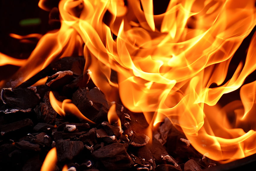 Close-up of vibrant orange flames burning charcoal embers