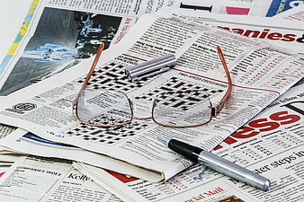 Eyeglasses and pen on newspaper crossword puzzle