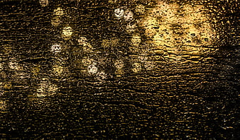 Golden raindrops on wet surface with bokeh lights