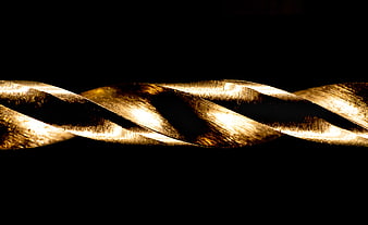 Macro shot of a gold drill bit spiral against a black background