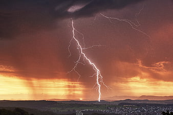 Dramatic Lightning Strike Over Rolling Hills at Sunset