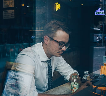 Contemplative businessman with glasses sitting in cafe window
