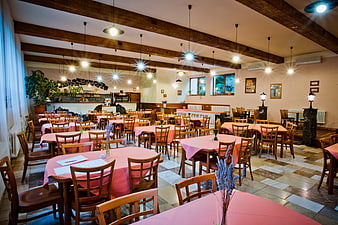 Spacious rustic restaurant interior with wooden beams and pink tablecloths