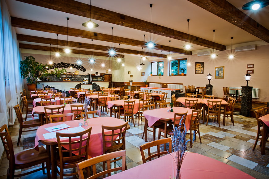 Spacious rustic restaurant interior with wooden beams and pink tablecloths