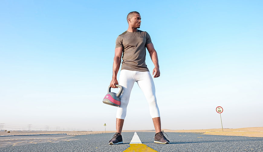 Athletic Man Holding Kettlebell on Desert Road