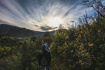Hikers walking on mountain trail with dramatic sky