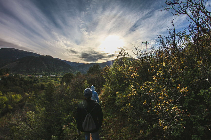 Hikers walking on mountain trail with dramatic sky