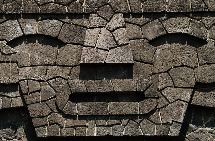 Stone Mosaic Face Sculpture On Textured Wall