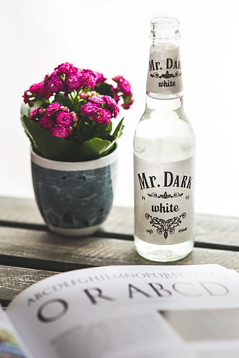 Mr. Dark White Cola Bottle with Pink Flowers on Wooden Table