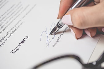 Close-up of Hand Signing Document with Silver Pen