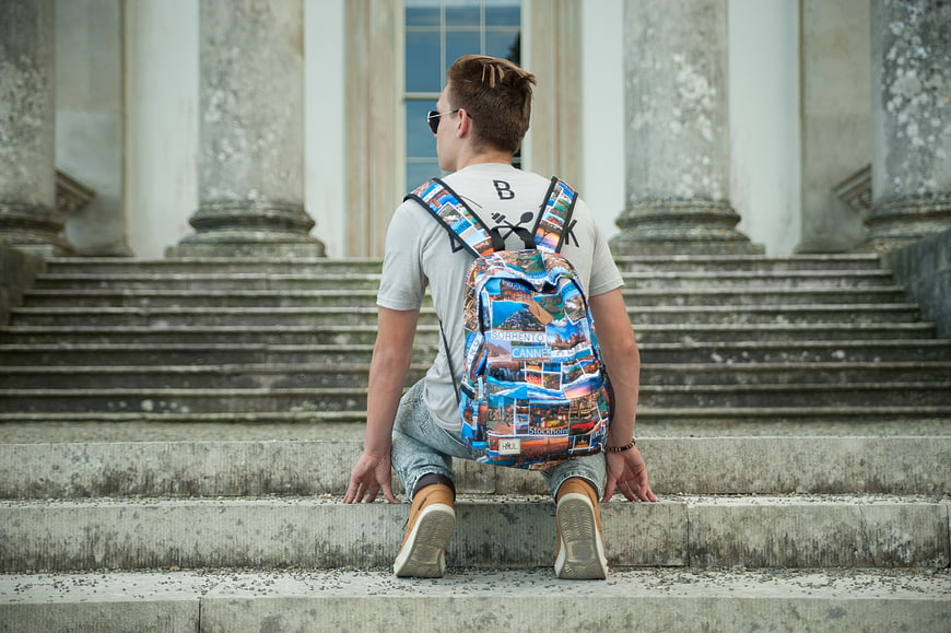 Young Traveler with Backpack Sitting on Stone Steps