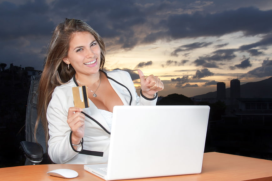 Smiling Businesswoman with Credit Card and Laptop at Sunset