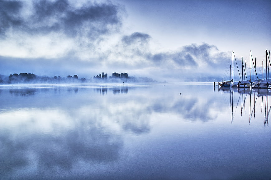 Serene Misty Lake Landscape with Sailboats and Reflections