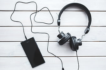 Black headphones and smartphone on white wooden background