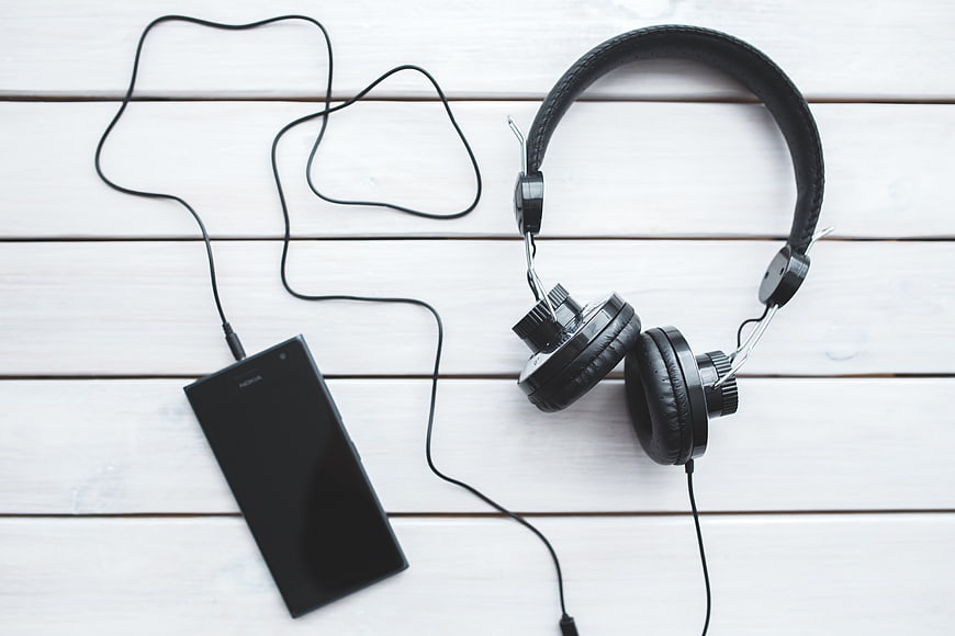 Black headphones and smartphone on white wooden background