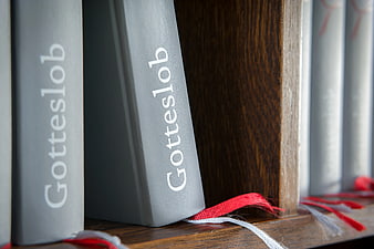 Close-up of Gotteslob hymnals on a wooden shelf