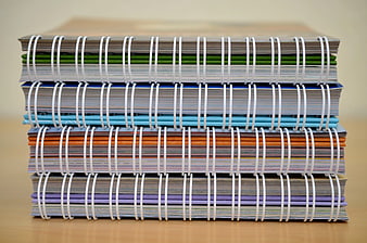 Stack of colorful spiral notebooks on wooden desk