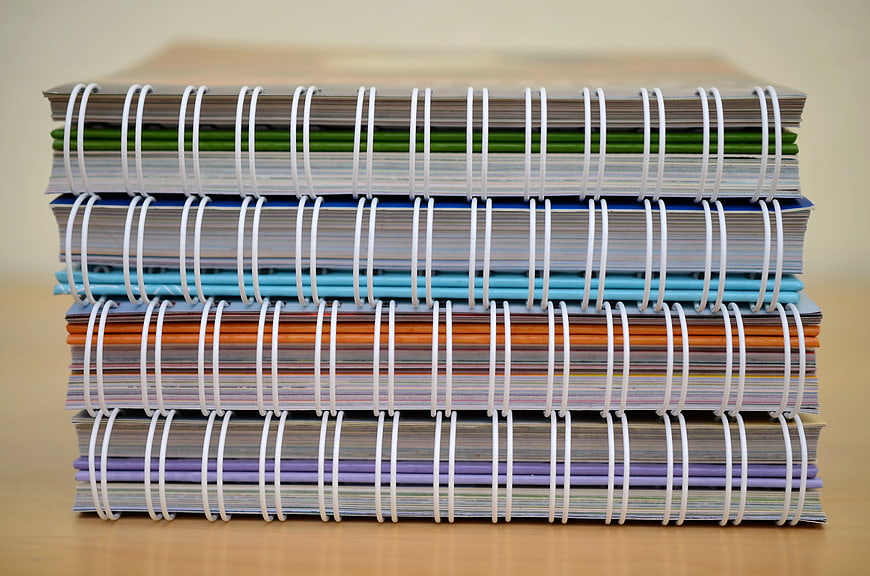 Stack of colorful spiral notebooks on wooden desk