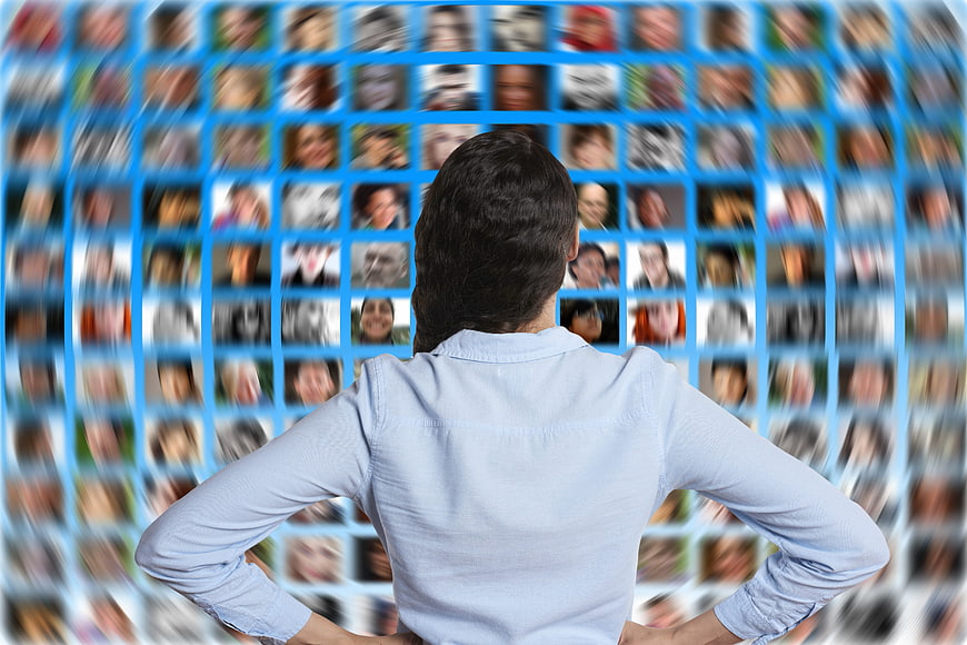 Woman facing digital network of blurred faces on blue background