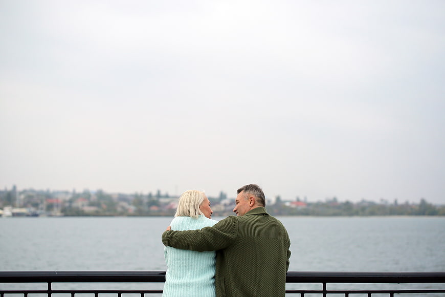Senior couple embracing by waterfront railing