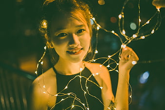 Smiling Asian Woman Holding Fairy Lights at Night