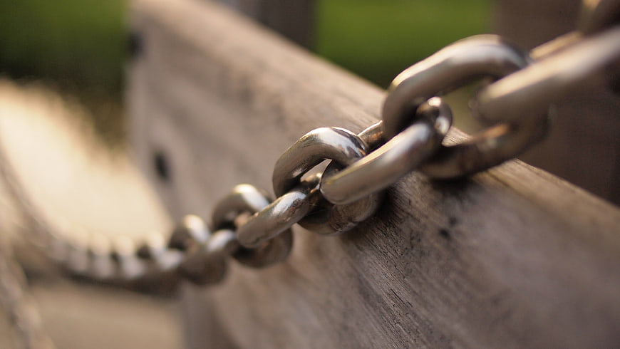 Close-up of metal chain links on weathered wood