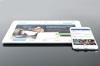 White tablet and smartphone displaying responsive website on gray surface