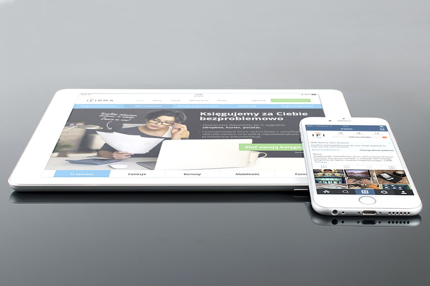 White tablet and smartphone displaying responsive website on gray surface