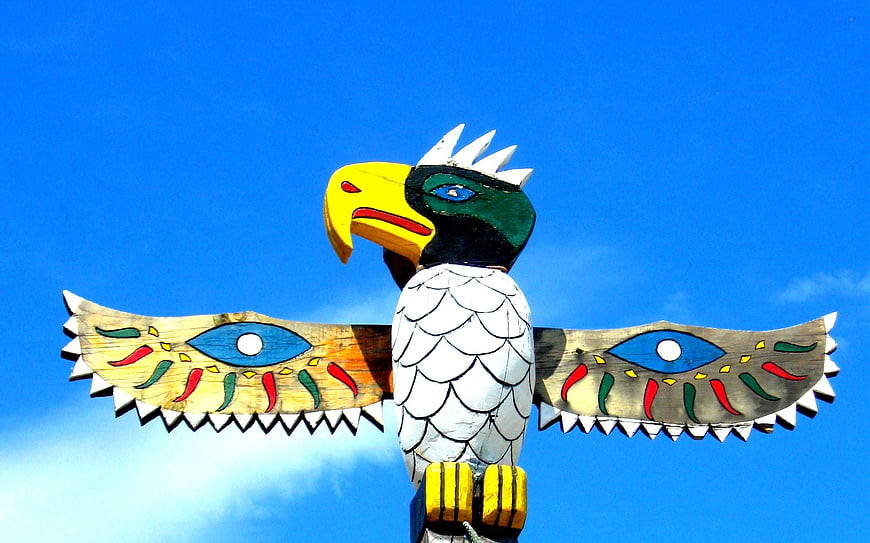 Colorful Painted Wooden Eagle Sculpture Against Blue Sky