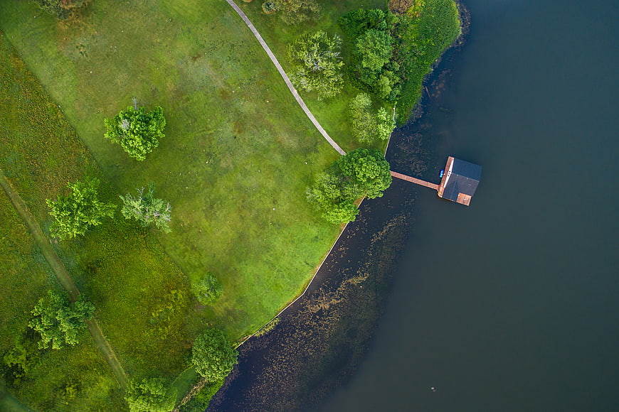 Aerial view of green park with pier and lake