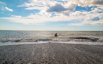 Man Walking in Ocean Waves on Sandy Beach