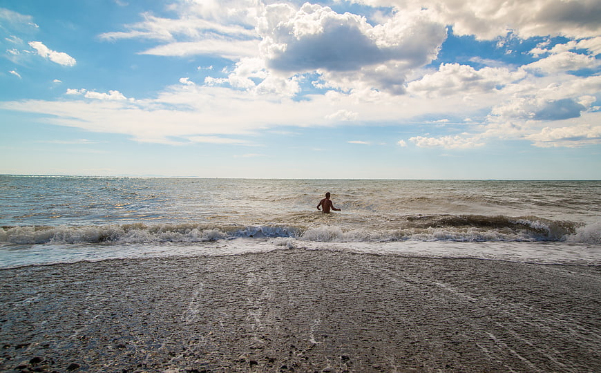 Man Walking in Ocean Waves on Sandy Beach