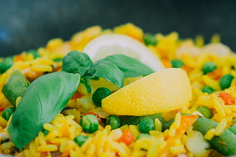 Close-up of yellow rice dish with peas, lemon, and basil