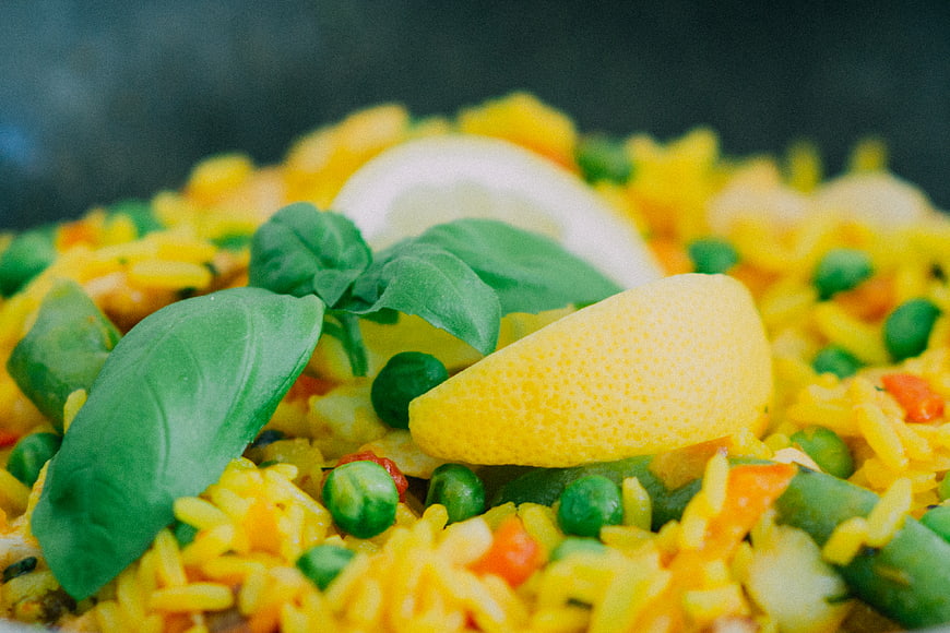 Close-up of yellow rice dish with peas, lemon, and basil