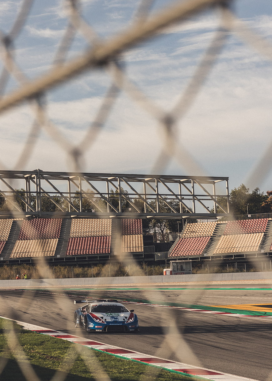 Race car speeding on track seen through safety fence
