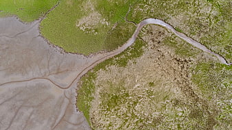 Aerial view of winding river channel through green marshland