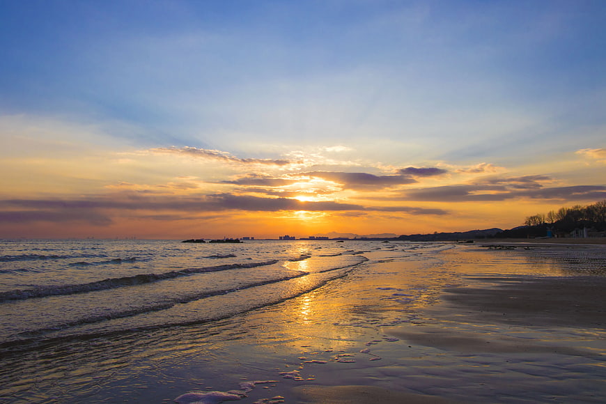 Golden Sunset Over Ocean Waves and Sandy Beach