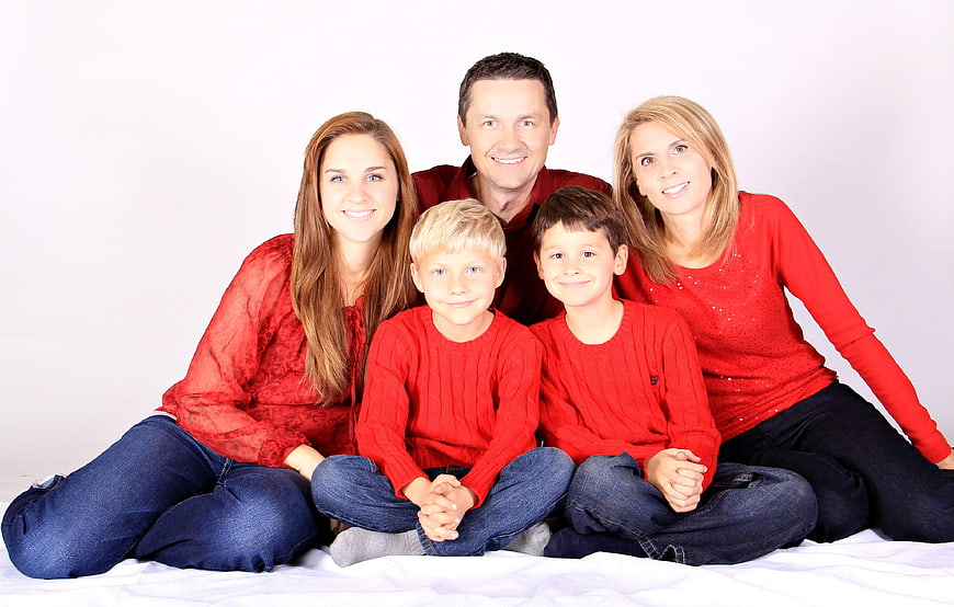 Happy family portrait in red sweaters sitting on white background