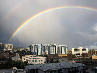 Vibrant Rainbow Arching Over Urban Cityscape