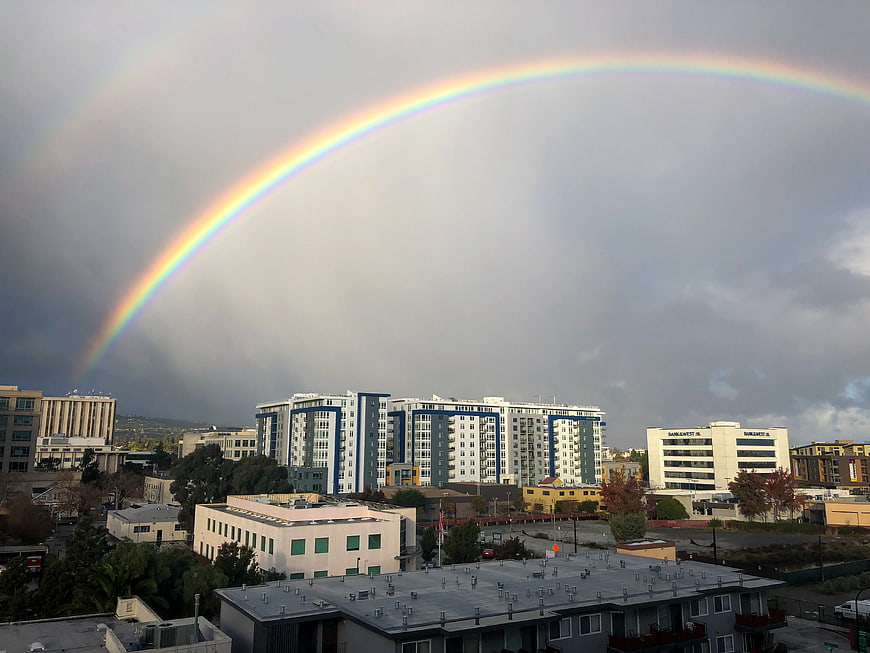 Vibrant Rainbow Arching Over Urban Cityscape