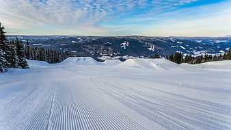Groomed ski slope with snow park jumps and mountain view