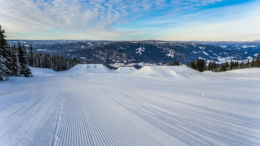 Groomed ski slope with snow park jumps and mountain view