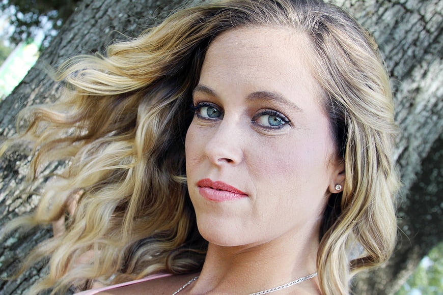 Close-up Portrait of Blonde Woman Leaning Against Tree