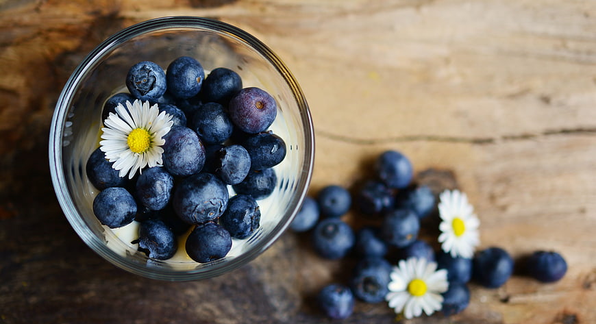 Top View of Fresh Blueberries in Glass Bowl with Daisies