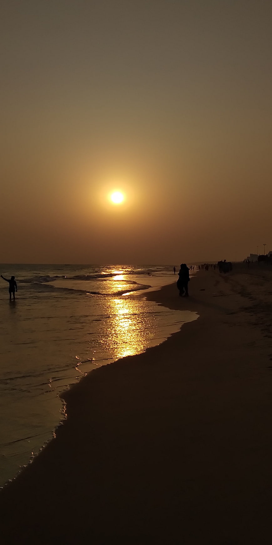 Silhouettes of people on a beach during a golden sunset