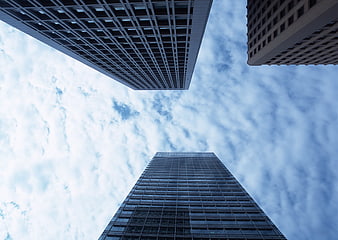 Low angle view of modern skyscrapers against cloudy blue sky