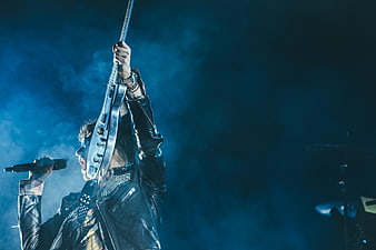 Rock musician performing live on stage with electric guitar and microphone