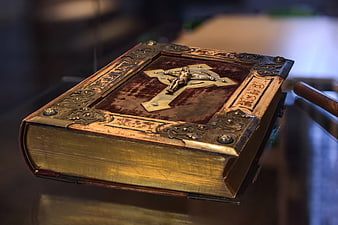 Antique leather-bound Bible with ornate gold cross and crucifixion relief